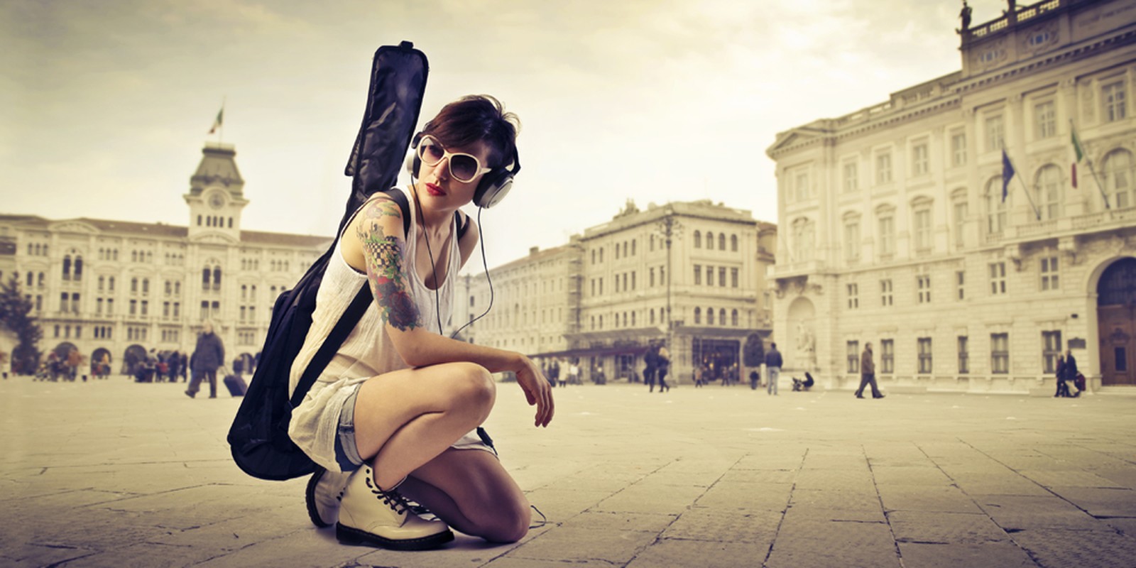 Junge Frau mit Gitarrentasche auf dem Rücken