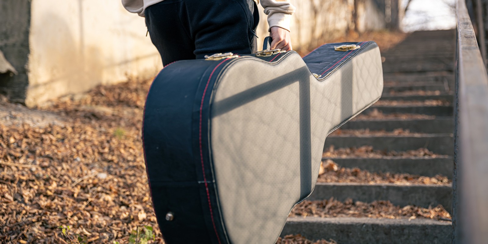 Person trägt Koffer für Akustikbass in der Hand