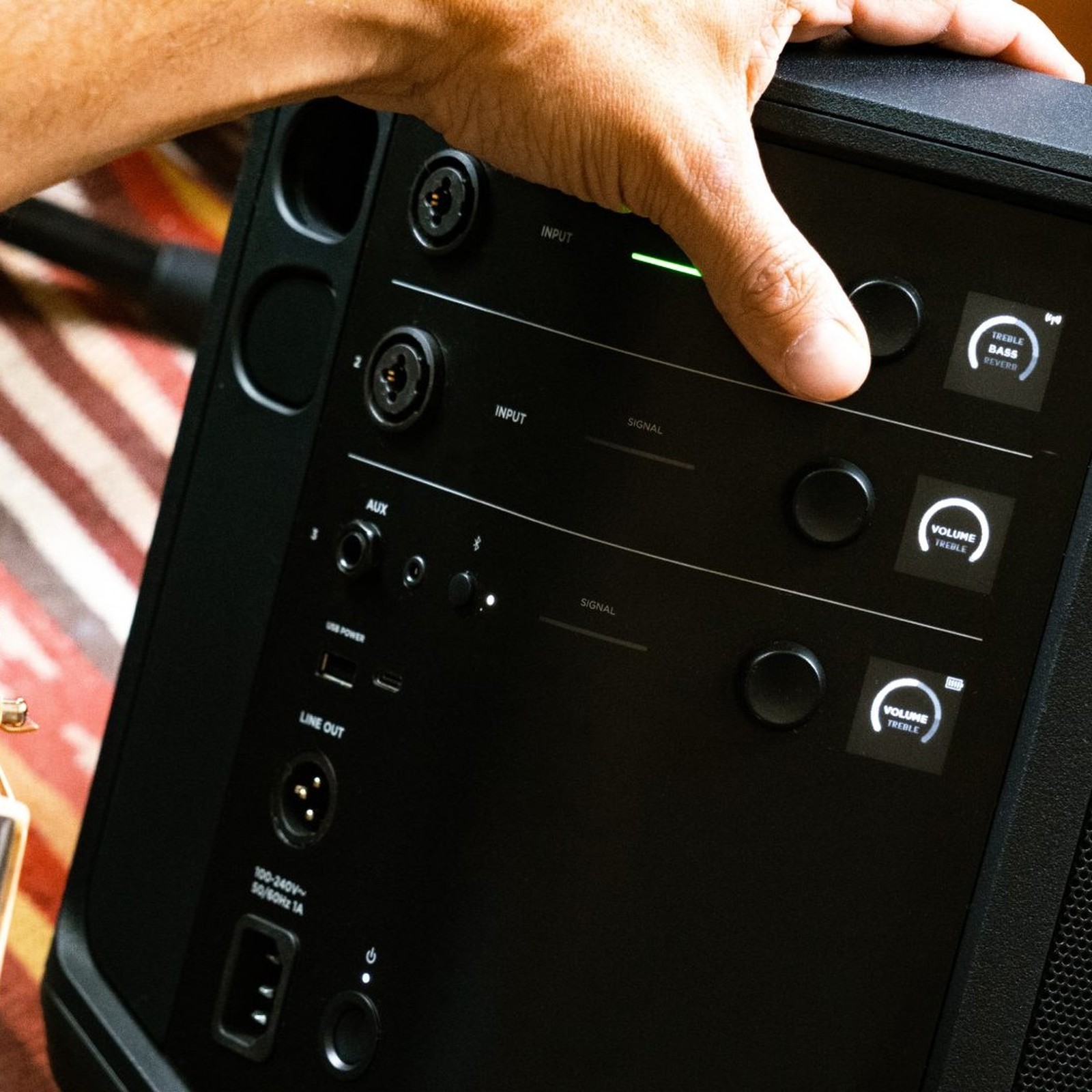 Hand operating the control knobs on the rear side of the Bose S1 Pro Plus