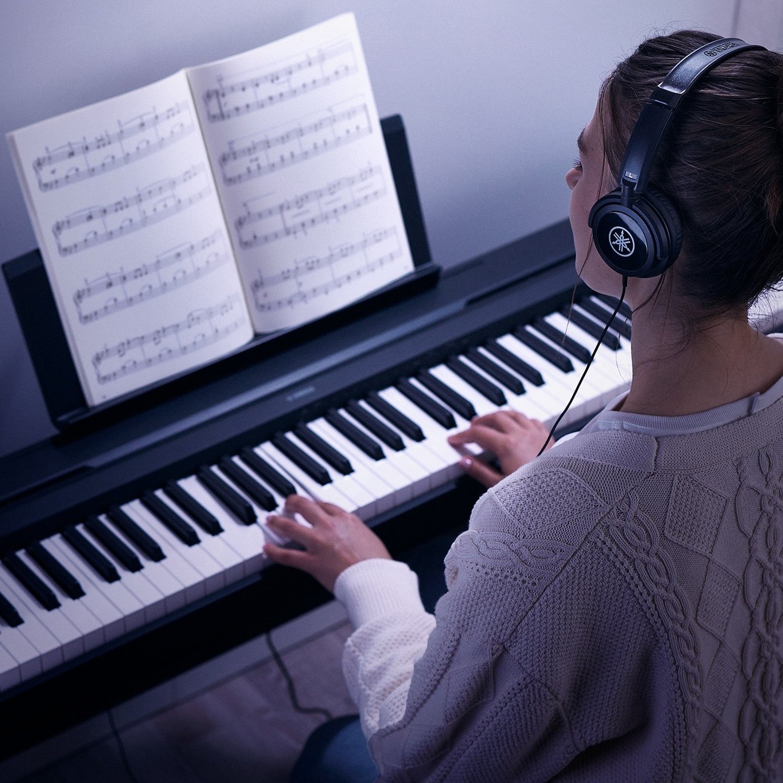 Pianistin spielt mit Kopfhörern auf dem Yamaha P-45 B