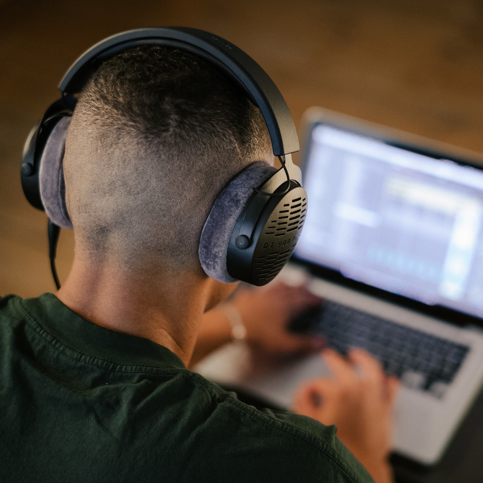 Mężczyzna siedzący przy laptopie ze słuchawkami beyerdynamic DT 900 Pro X