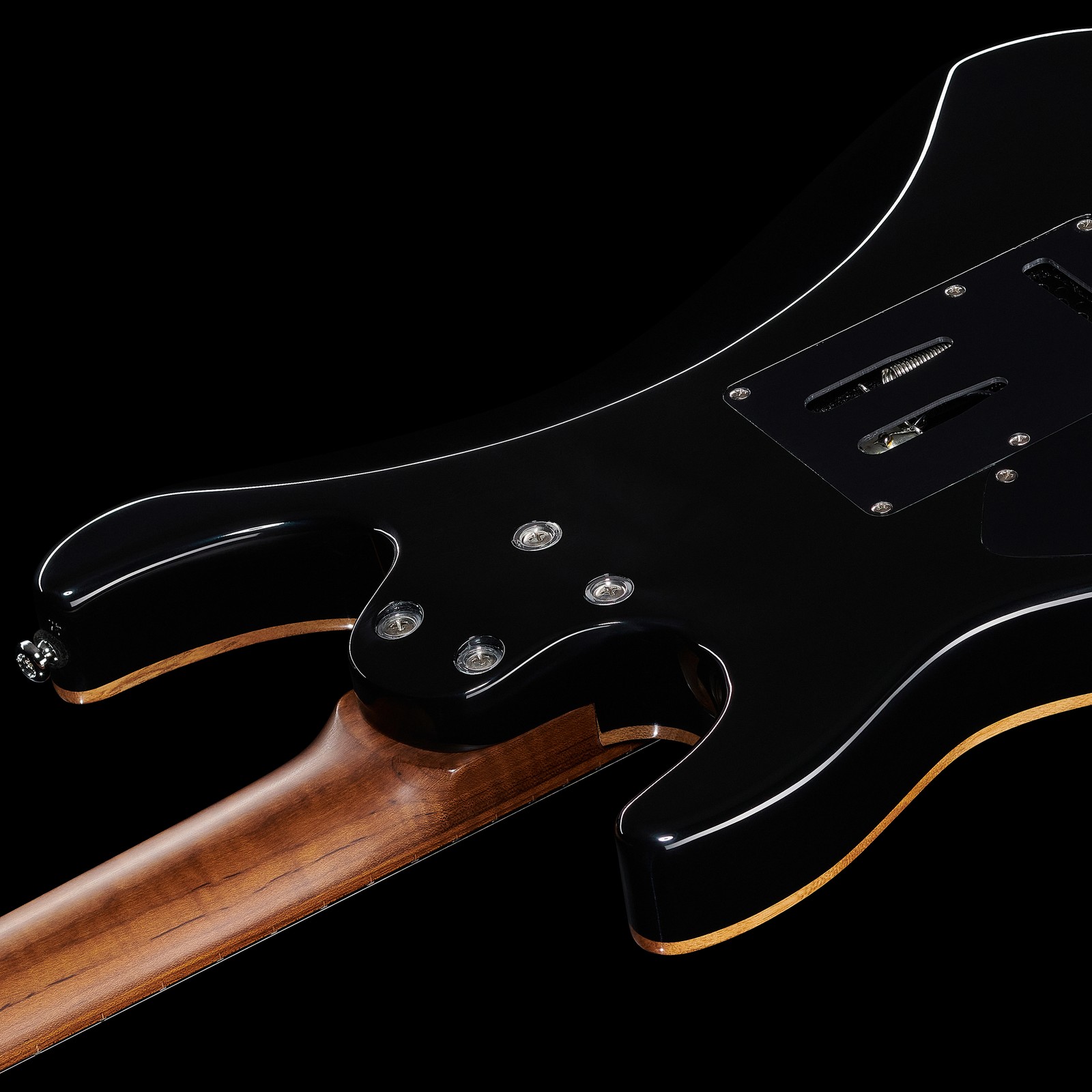 Vue de derrière du corps noir de la guitare électrique vissé au manche en érable ondé
